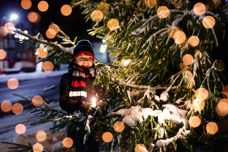 Gutt som leker med et juletre på marked.