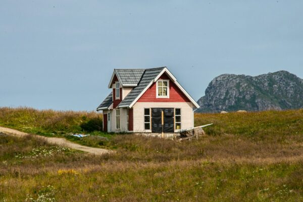 Lite hus i svart og hvitt på en grønn gressmark i Norge