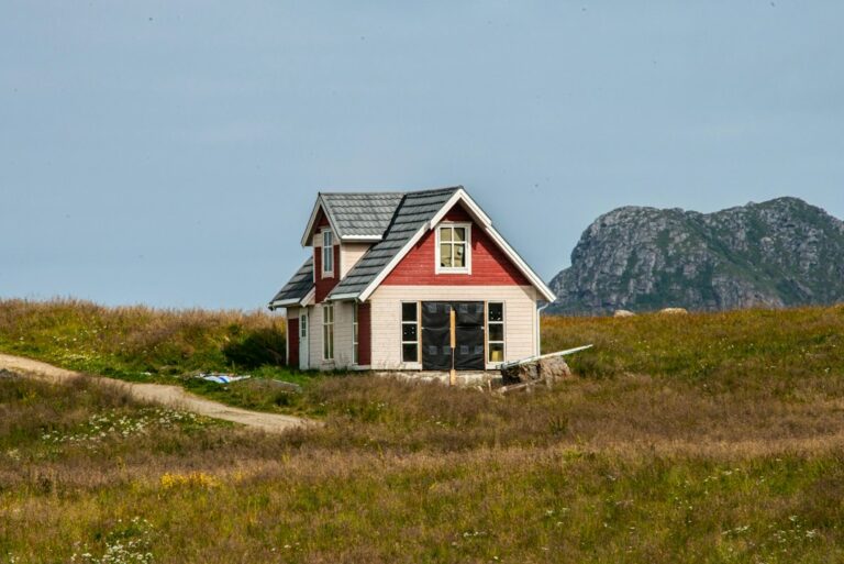 Lite hus i svart og hvitt på en grønn gressmark i Norge