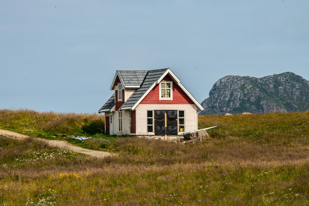Lite hus i svart og hvitt på en grønn gressmark i Norge