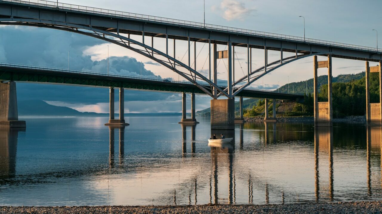 A bridge arches over calm water.