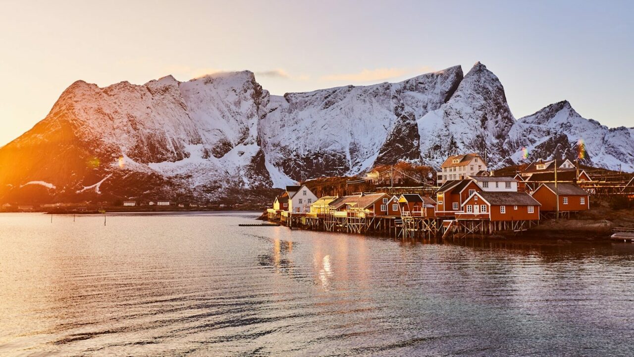 brown wooden house on body of water near mountain during daytime