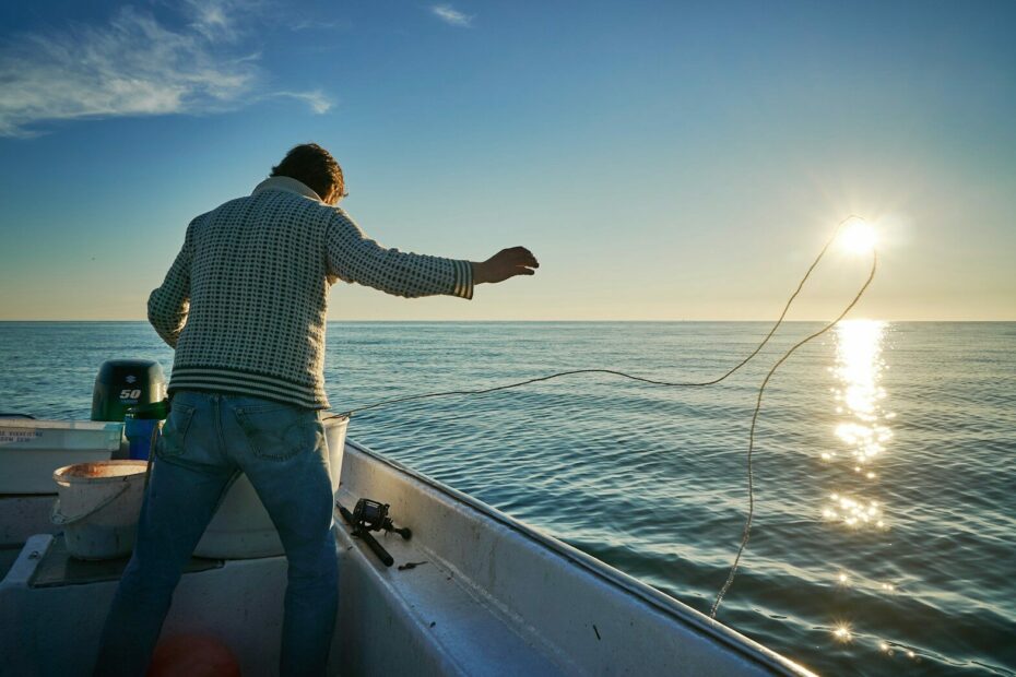 man standing on boat throwing rope on water