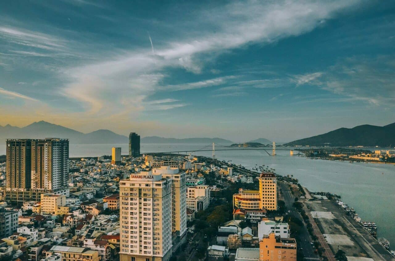 Da Nang i Vietnam med bysentrum, fjell, elv og bro ved solnedgang.